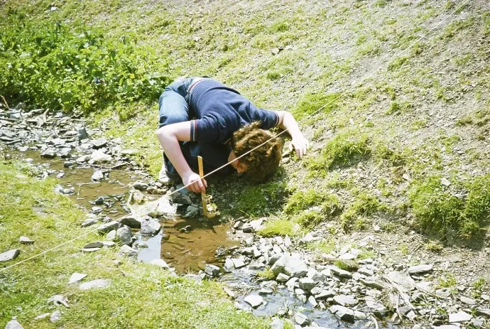 Framed Print : Secondary school student doing geographical fieldwork, Great Britain 1970s: Girl measuring the depth of a small stream with a ruler, 1977