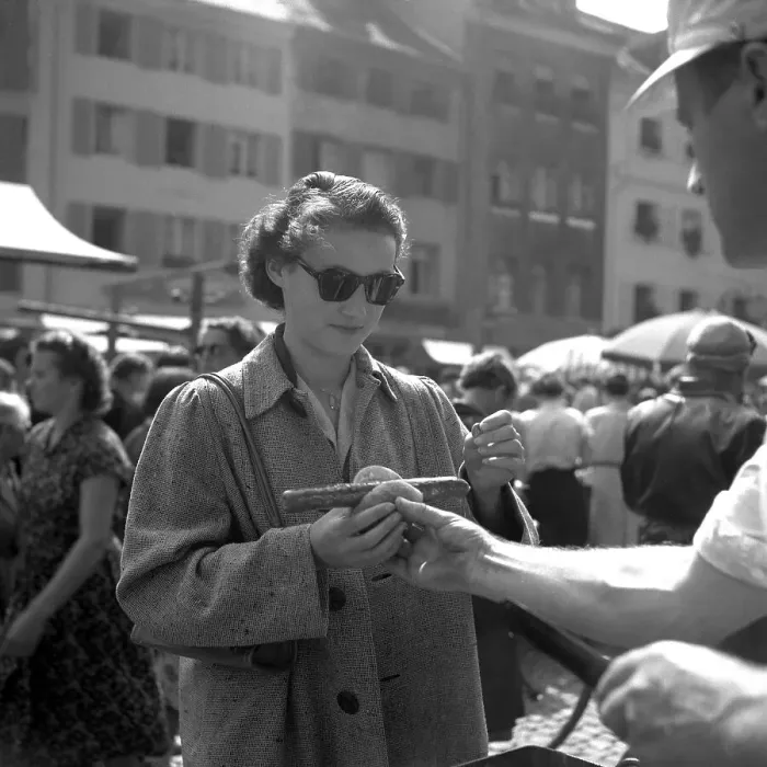 Framed Print : Seller hands a woman a sausage in bread Framed Print : Seller hands a woman a sausage in bread