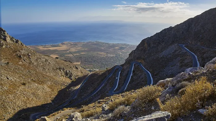 Framed Print : Serpentine road winds through a dry mountainous landscape down to the sea