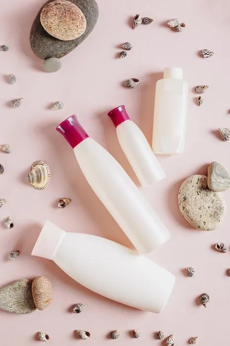 Framed Print : Set of bottles with cosmetic products among stones and shells on pink top and vertical view