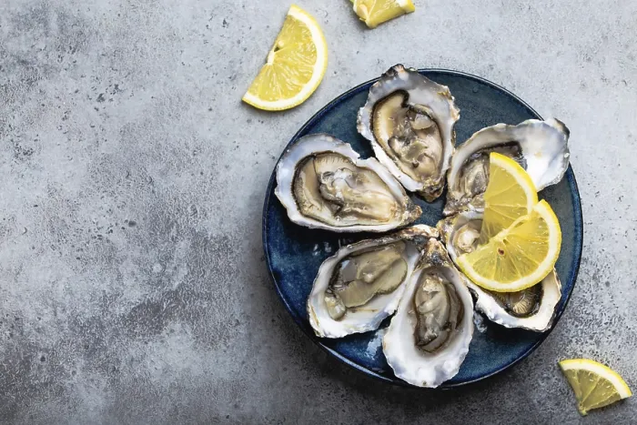Framed Print : Set of half dozen fresh opened oysters in shell with lemon wedges served on rustic blue plate on gray stone background