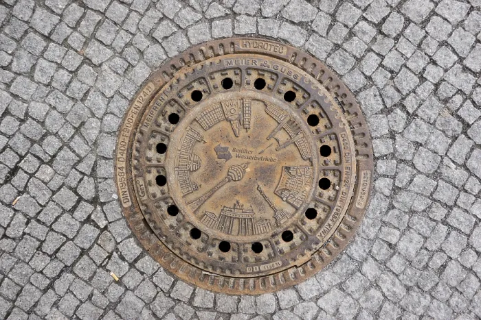 Framed Print : Sewer cover of Berliner Wasserbetriebe with architectural sights of the capital Framed Print : Sewer cover of Berliner Wasserbetriebe with architectural sights of the capital