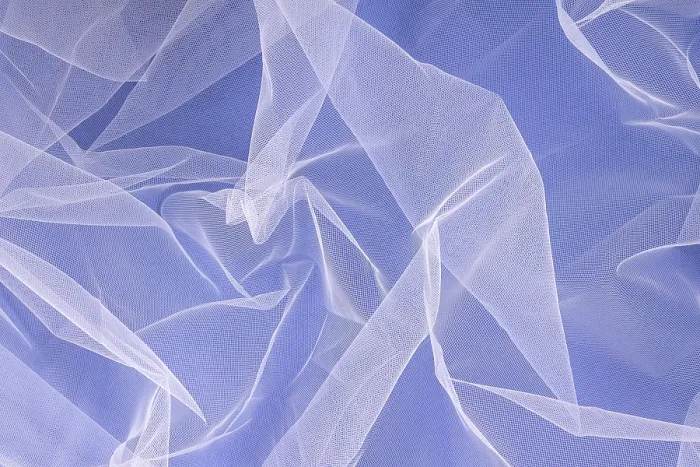 Framed Print : Sheer tulle fabric arranged in soft folds on a blue background
