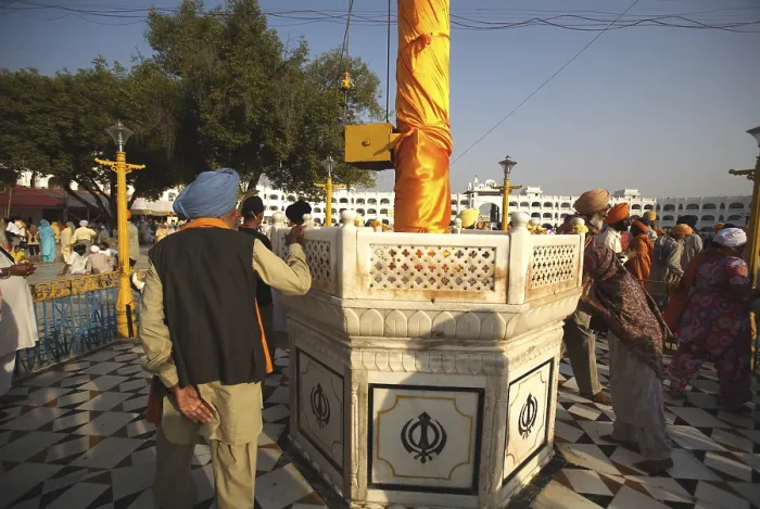 Framed Print : Sikh devotee paying his respect to Nishansahib compound of Sachkhand Saheb Gurudwara