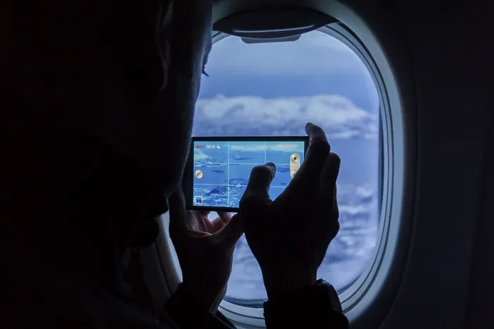 Framed Print : Silhouette of a man taking photos of the mountains using a smartphone from an airplane window Framed Print : Silhouette of a man taking photos of the mountains using a smartphone from an airplane window