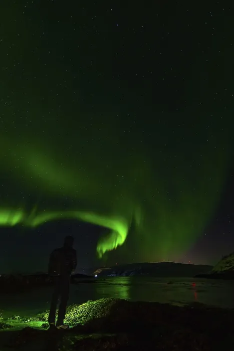 Framed Print : A silhouette by water reflecting stunning green auroras under night skies