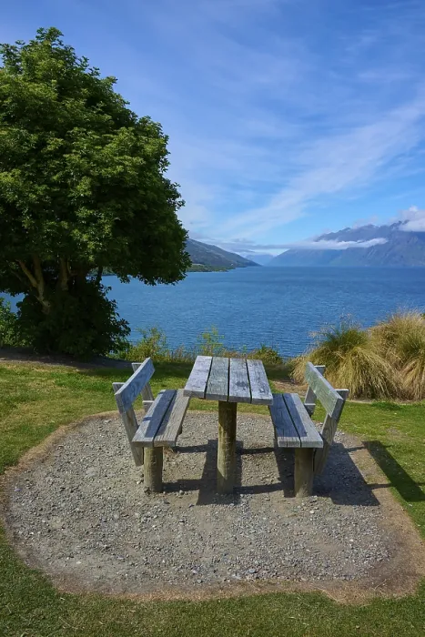 Framed Print : Single picnic table overlooking lake and mountains in scenic setting