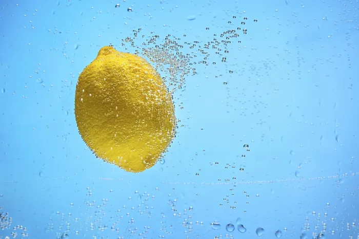 Framed Print : Single yellow lemon covered with air bubbles floating in blue water