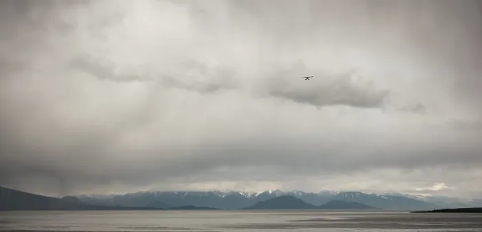 Framed Print : A small airplane flies over a wide area with distant mountains as seen from deck of passenger ferry crossing the Salish