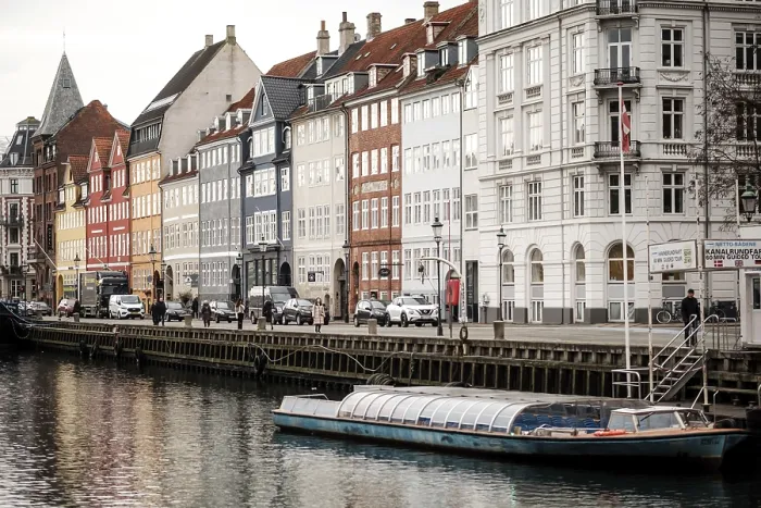 Framed Print : A small boat moored along a canal flanked by rows of colorful buildings in Nyhavn