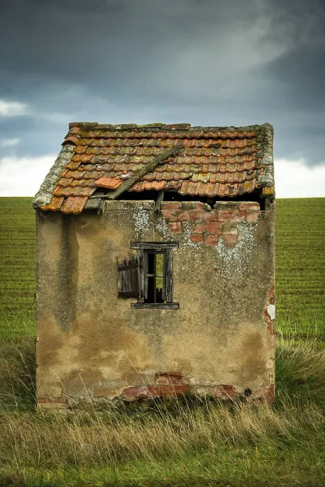 Framed Print : A small, dilapidated hut with a broken roof and cracked walls sits alone in a vast green field