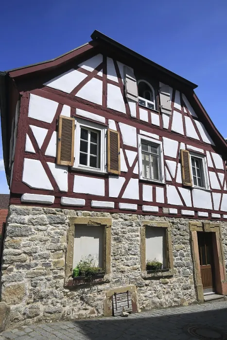Framed Print : Small half-timbered house with red beams and stone foundation