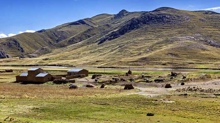 Framed Print : Small houses at the foot of mountains in a vast landscape under blue sky