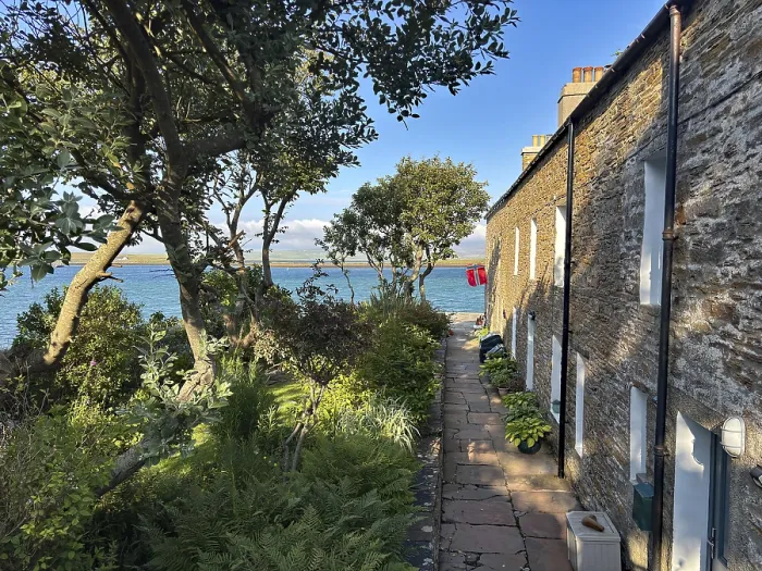 Framed Print : Small stone cottage with garden and sea view in sunny weather Framed Print : Small stone cottage with garden and sea view in sunny weather