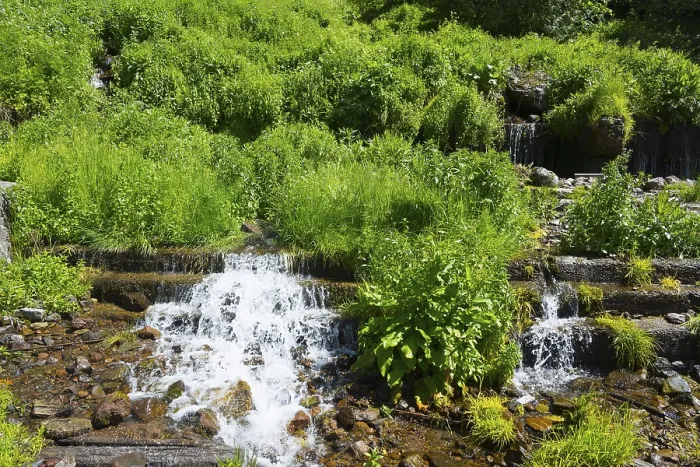 Framed Print : Small waterfall with lush green vegetation and rocky surroundings