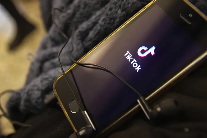 Framed Print : Smartphone displaying the TikTok app logo with tangled earbuds resting on it