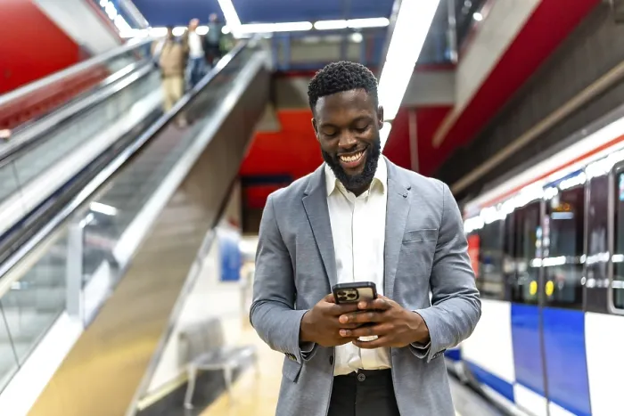 Framed Print : Smiling businessman using a smartphone while waiting for a train at an urban subway station