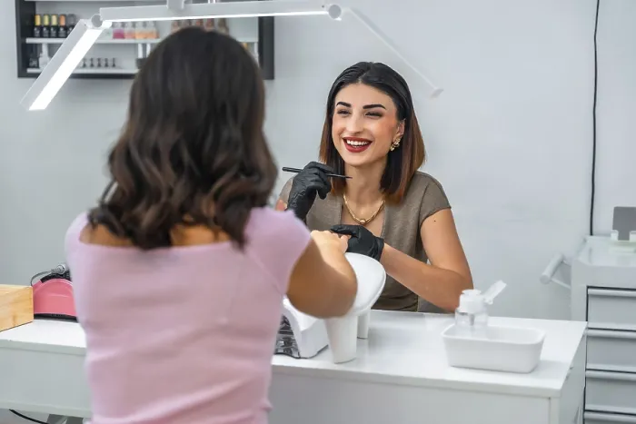 Framed Print : Smiling manicurist applying nail polish to her customer in a beauty salon