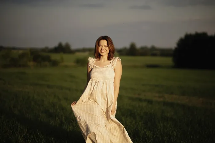 Framed Print : A smiling woman in a flowing dress stands in a field during sunset