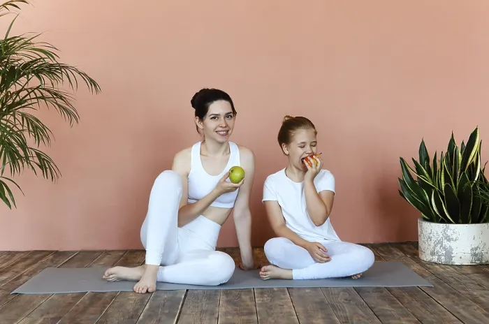 Framed Print : Smiling woman and little girl eating fruits after practicing yoga on mat in cozy living room