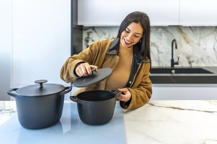 Framed Print : Smiling woman selecting a cooking pot in a bright home improvement store's kitchenware department