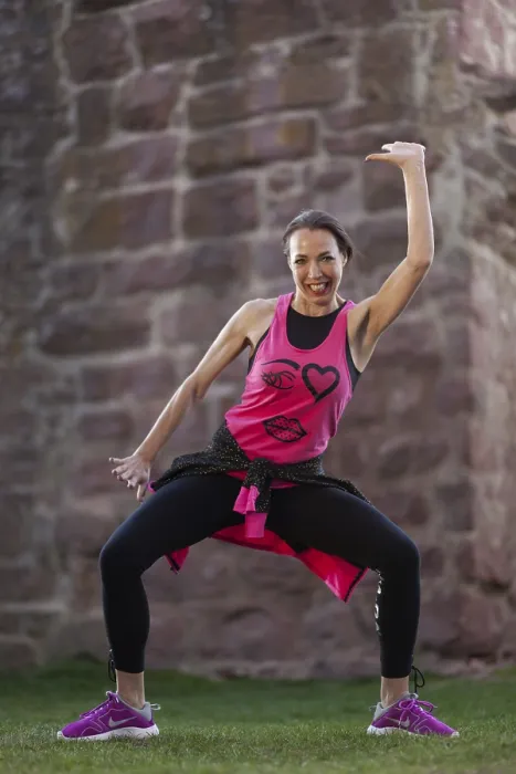 Framed Print : Smiling woman in sportswear in dynamic Zumba pose in front of a stone wall