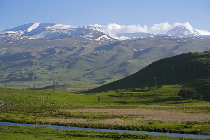 Framed Print : Snow-capped mountains rise above a green valley while the sky is clear and blue