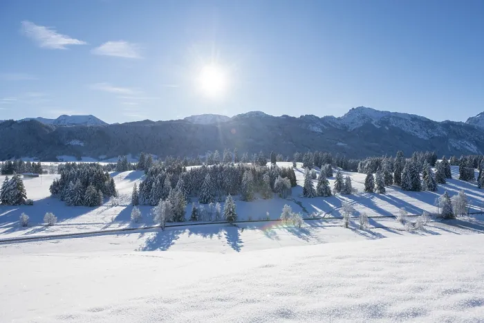 Framed Print : Snow-covered landscape with bright sun over mountains and trees