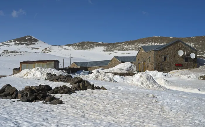 Framed Print : Snow-covered landscape with stone and metal buildings under a clear blue sky