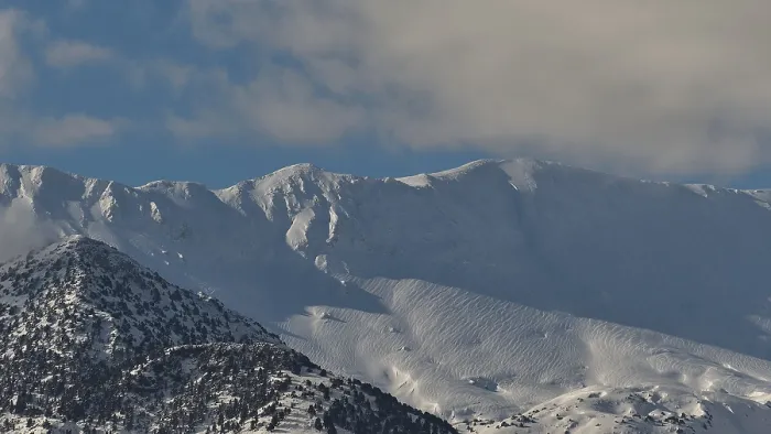 Framed Print : Snow-covered mountain peaks under a clear blue sky with scattered clouds