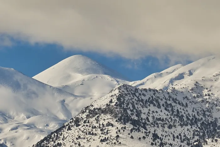 Framed Print : Snow-covered mountain peaks silhouetted against a clear blue sky with a few clouds