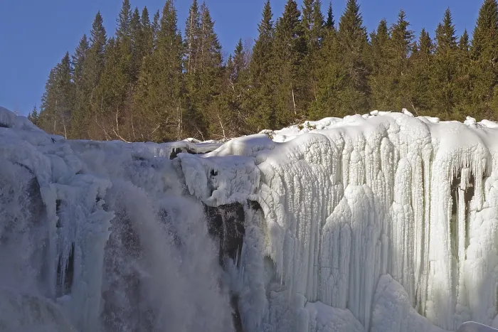 Framed Print : Snow-covered trees surround a frozen waterfall with impressive ice structures