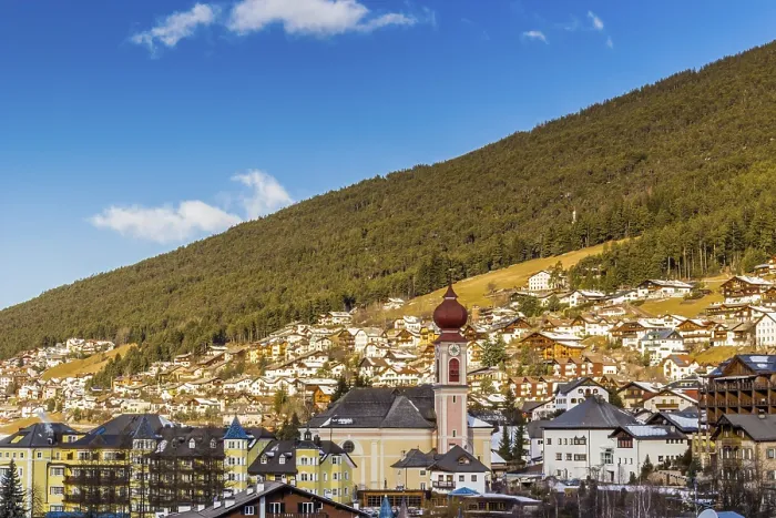 Framed Print : Snowy alpine village in Italy illuminated by sun with mountains in the background