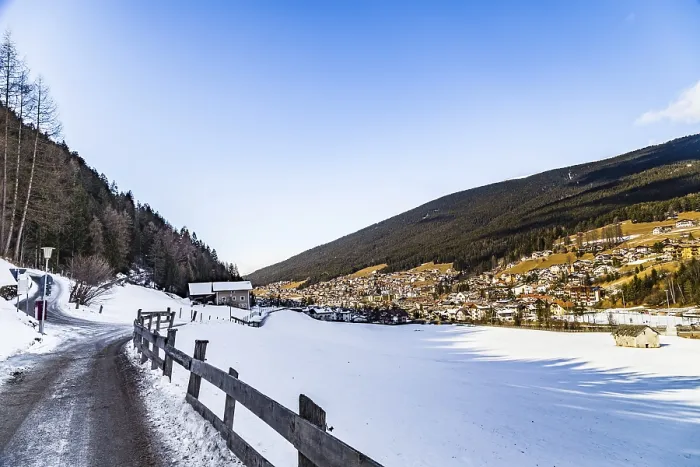 Framed Print : Snowy alpine village in Italy illuminated by sun with mountains in the background