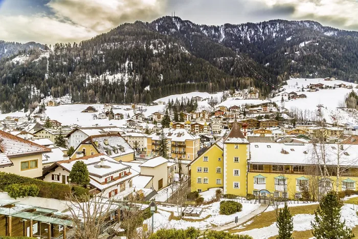 Framed Print : Snowy alpine village in Italy illuminated by sun with mountains in the background