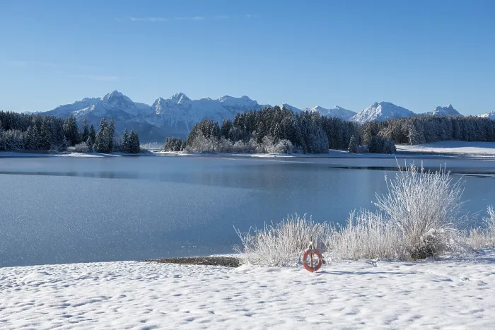 Framed Print : Snowy lake with mountains in the background under blue sky