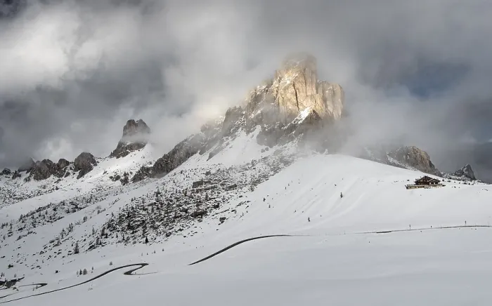 Framed Print : Snowy mountain landscape with dramatic clouds and sunlight illuminating rugged peaks