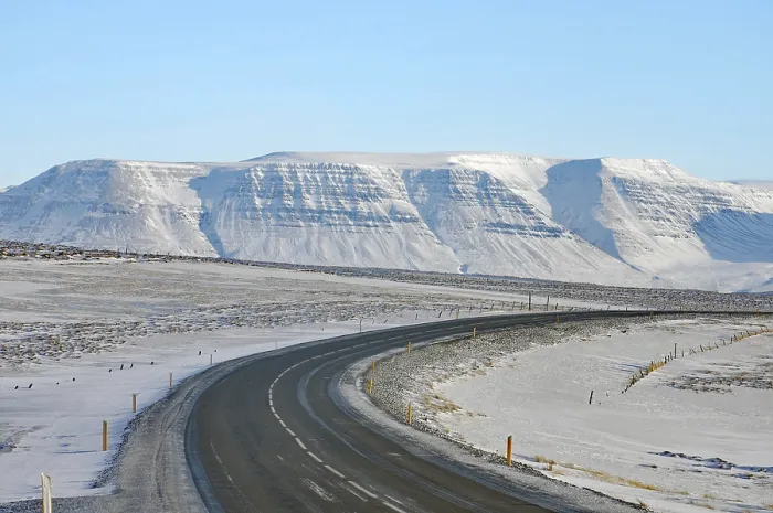 Framed Print : Snowy road leads to a snow-covered mountain range under a clear blue sky