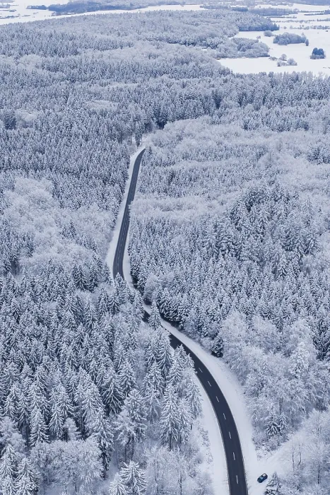 Framed Print : Snowy road snakes through a thick winter forest