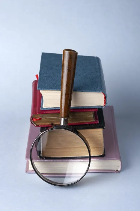 Framed Print : A stack of hardcover books and a magnifying glass on a blue background Framed Print : A stack of hardcover books and a magnifying glass on a blue background