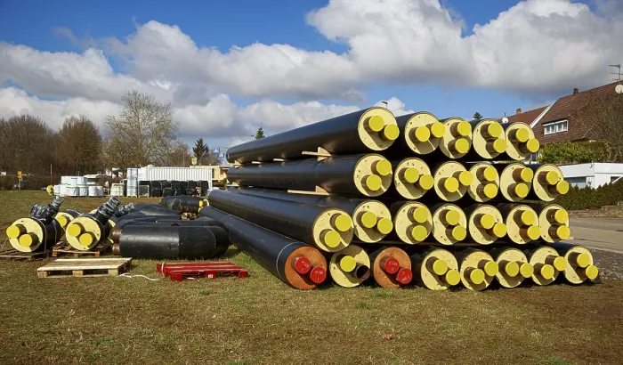 Framed Print : Stacked district heating pipes and district heating lines with yellow ends lie piled up in a meadow
