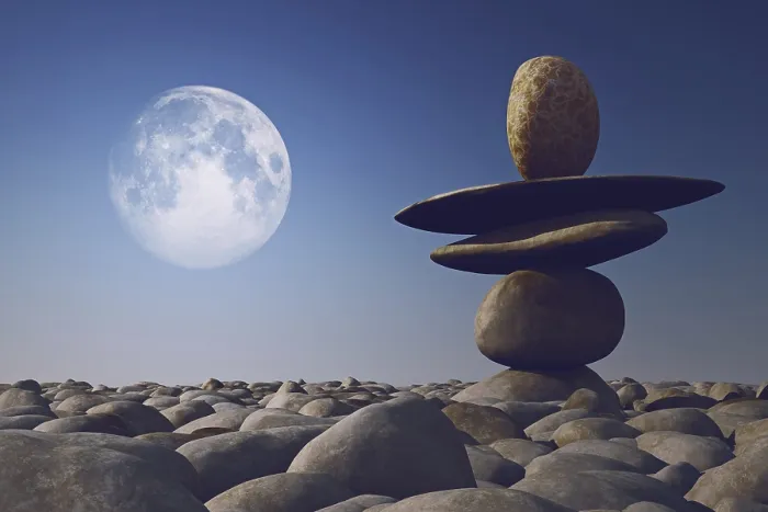 Framed Print : Stacked stones in sunlight with moon in sky on pebble sea beach