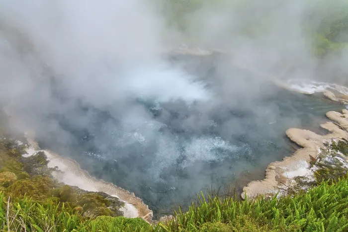 Framed Print : Steaming hot spring with blue water surrounded by green vegetation and rocks