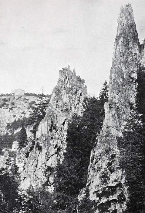 Framed Print : Steep and high rocks protrude from a wooded area