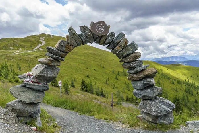 Framed Print : Stone arch marks the entrance to a hiking trail in the middle of a green hilly landscape