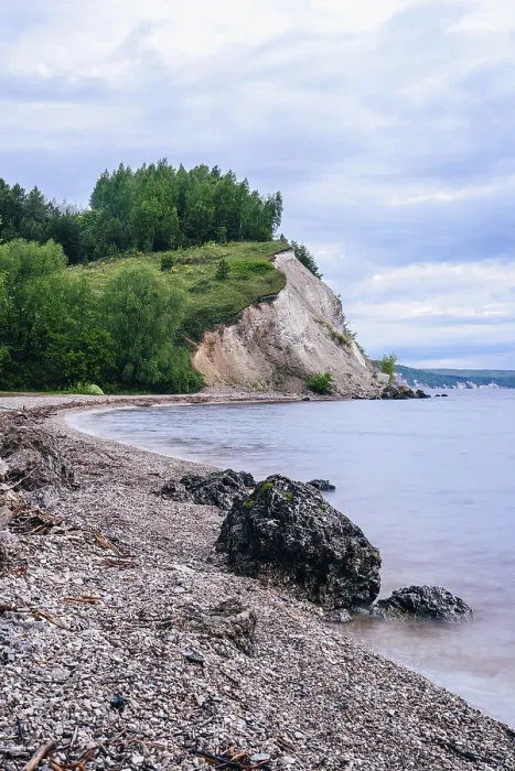 Framed Print : Stone on the riverbank and cliff with birch woodland on background
