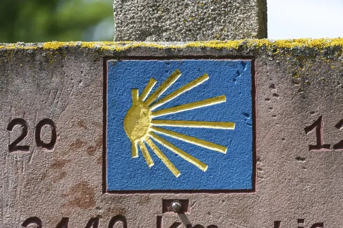 Framed Print : Stone slab with blue shell, showing pilgrims on the Way of St James the way to Santiago de Compostela