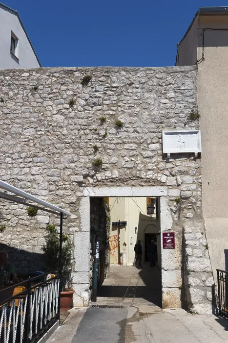 Framed Print : Stone wall with archway leads into a narrow