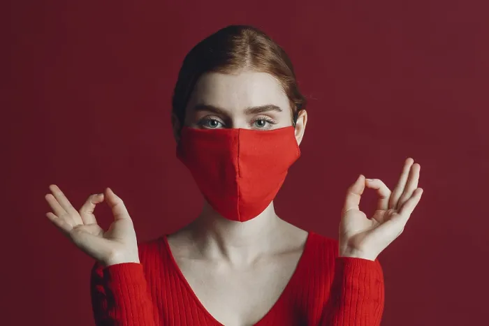 Framed Print : Studio portrait of young woman in protective medical face mask isolated on red background