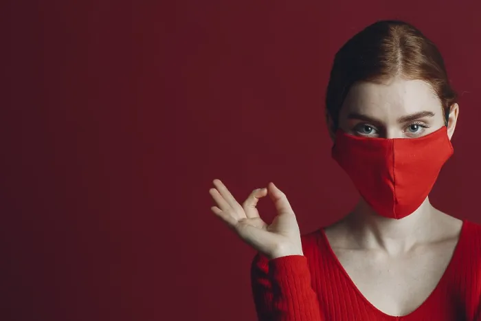 Framed Print : Studio portrait of young woman in protective medical face mask isolated on red background